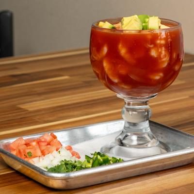 Shrimp cocktail with avocado, served with diced tomatoes, onions, and cilantro.