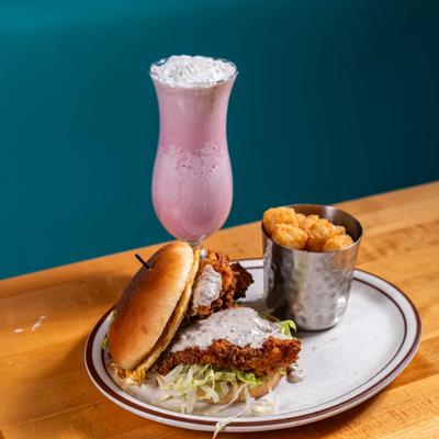 Chicken sandwich served with tater tots and a shake.