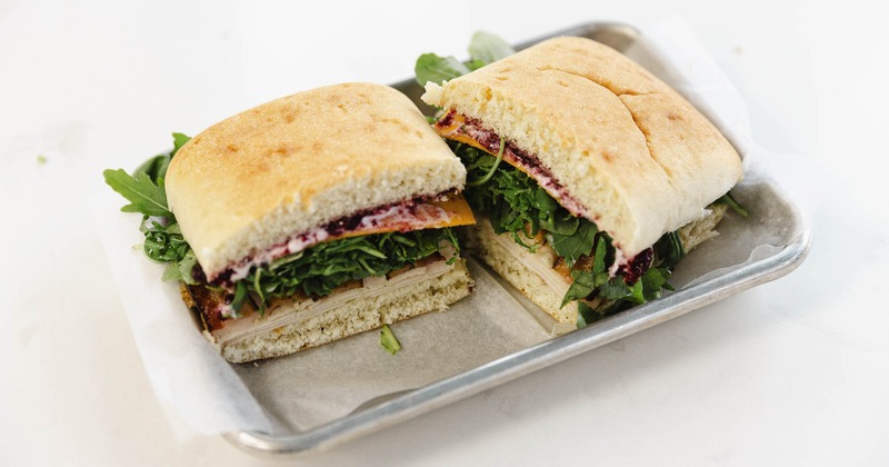 Sandwich with turkey, bacon, cheddar, arugula, herbs, and cranberry sauce