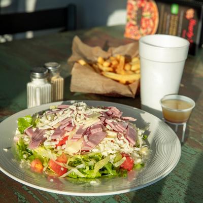 Chef Salad with fries, condiments, and a drink in the background.