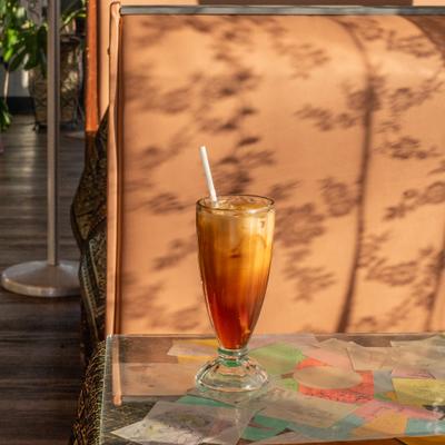 Thai iced tea on sunlit glass tabletop.