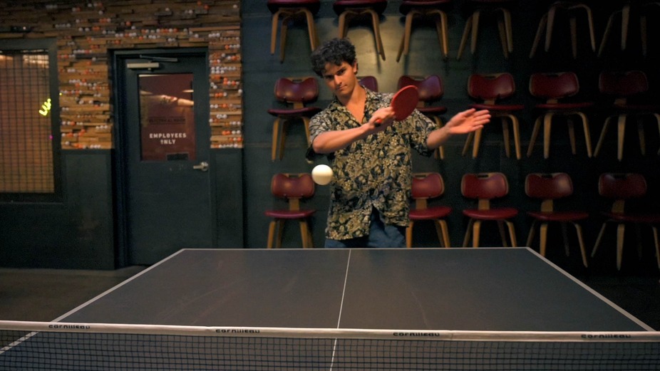 A guest swings a ping pong paddle during a game of table tennis.