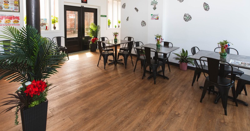 A bright restaurant interior with wooden flooring, black metal tables and chairs