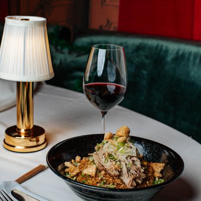 Chino latino fried rice on a table and a glass of red wine.