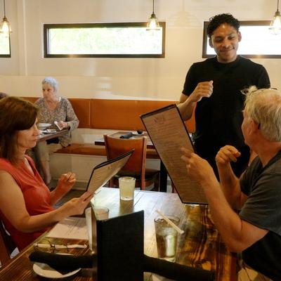 A server takes an order from customers looking at menus in the restaurant.