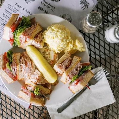 Club sandwich paired with potato salad and pickle.