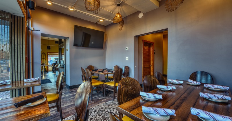 Interior, modern dining space with wooden tables and chairs and TV on the wall