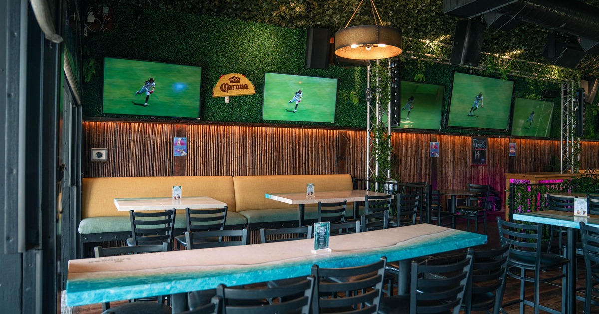 Sports bar seating area with multiple TVs and greenery