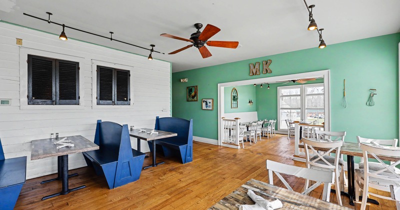 Bright restaurant interior with blue booths, wooden tables, and white chairs