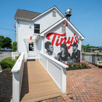 Restaurant building featuring a painted mural with the red signage and portraits of people.