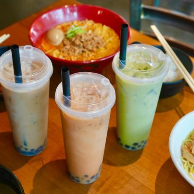 Three cups of Boba Tea served on the table with food.