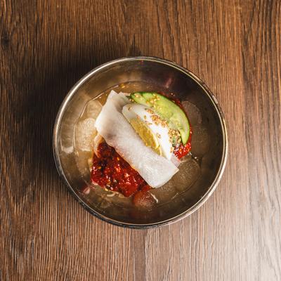 Spicy Korean cold noodle dish featuring cucumber, pickled radish, and a hard-boiled egg.