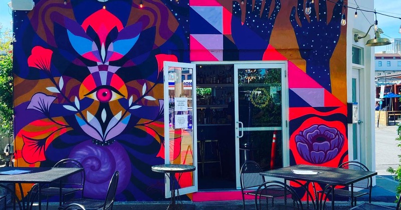 Exterior, colorful mural on the bar building, patio seating area in front