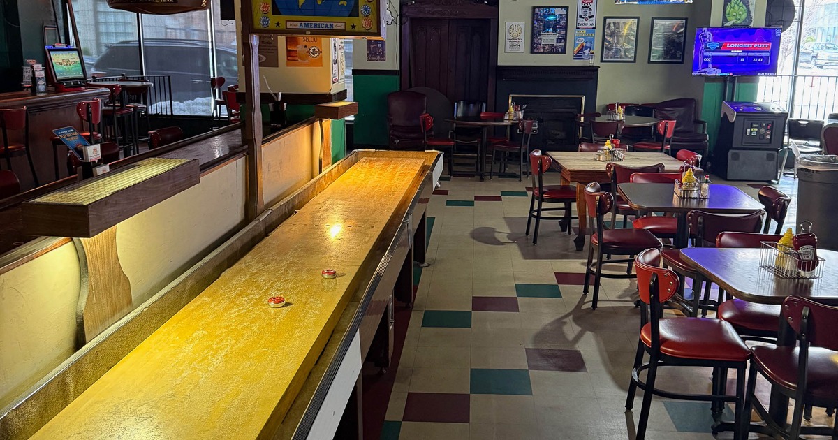 Bar interior with a shuffleboard table and dining area.