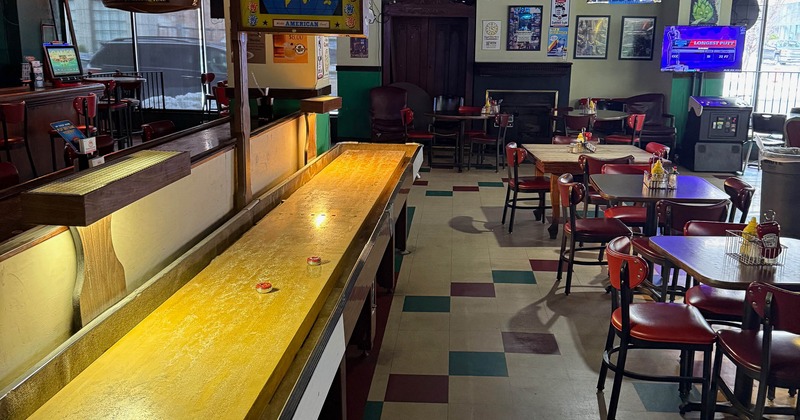Bar interior with a shuffleboard table and dining area.