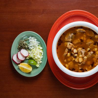 Pozole soup with a side of chile, oregano, onions & a lime wedge, top view