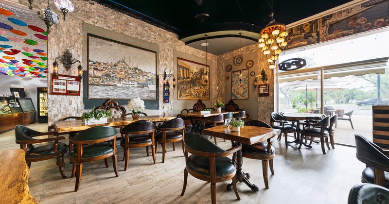 Interior of a stylish and cozy seating area with dark leather chairs and polished wooden tables