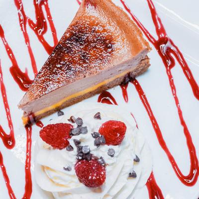 Cheesecake with raspberry  chocolate chip whipped cream and fruit drizzle.