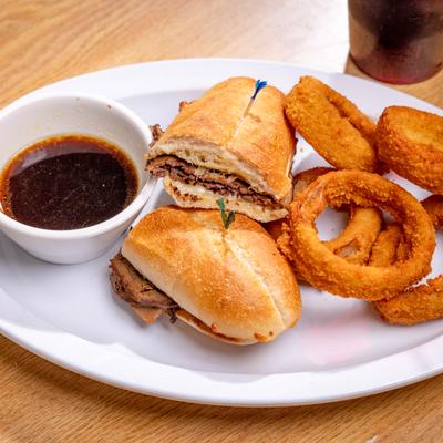 Roast beef sandwich served with onion rings and dipping broth.