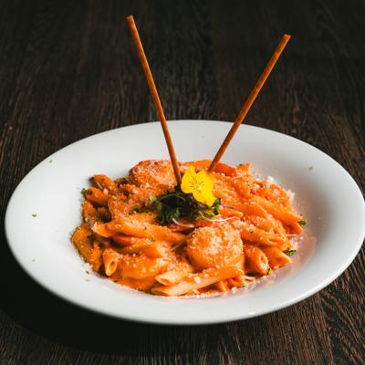 Penne Alla Vodka with Shrimp garnished with flowers and breadsticks.