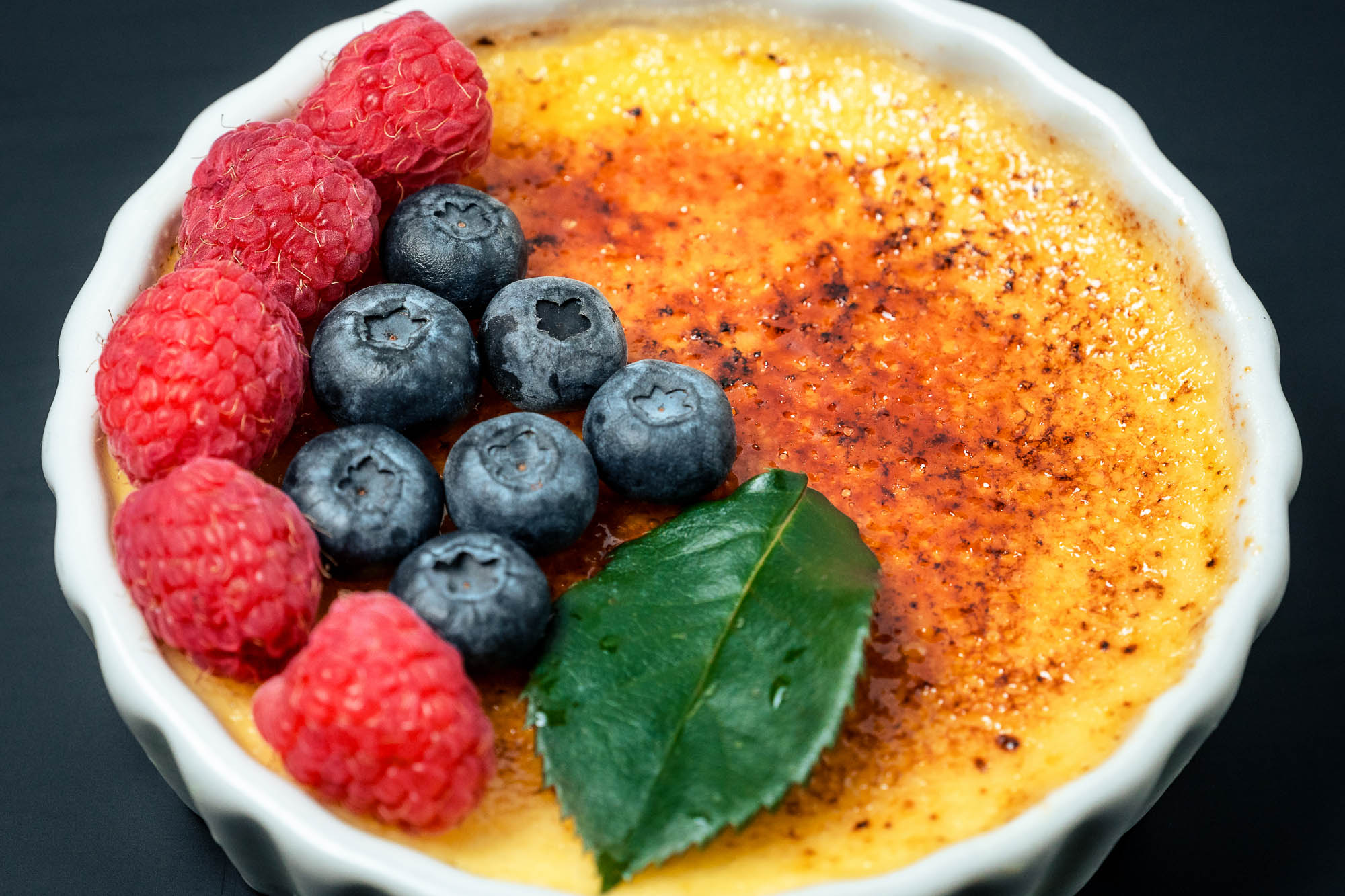 Creme brullee topped with berries, close-up view