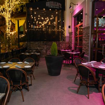 Outdoor patio set with multiple tables, chairs and a potted plant.