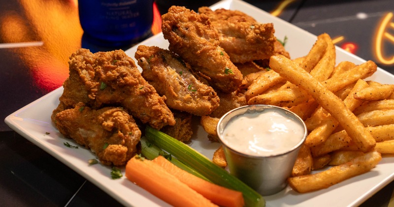 Fried chicken wings with celery, carrots, fries, and dip