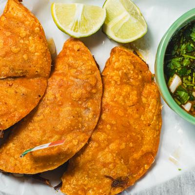 Quesa Birria served with consome and lome vedges, close-up.