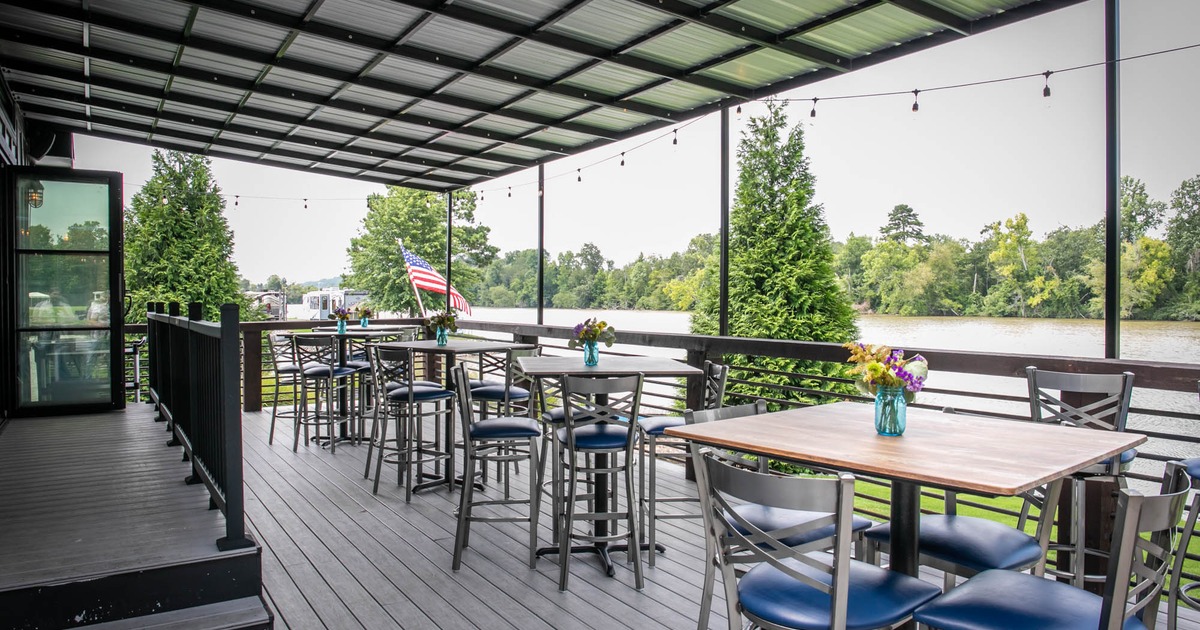 Exterior, covered seating area, high tables with stools, restaurant entrance