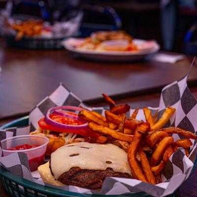 Cheeseburger with tomato and onion, accompanied by fries and ketchup.