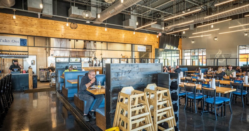 Interior, tables, chairs and blue leather high back benches, guests enjoying their food