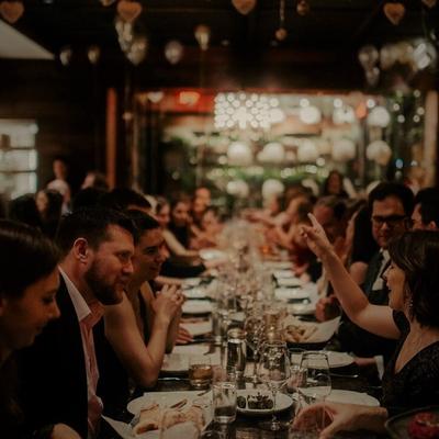 group of partygoers at a long table in the middle of Supra's dining room.
