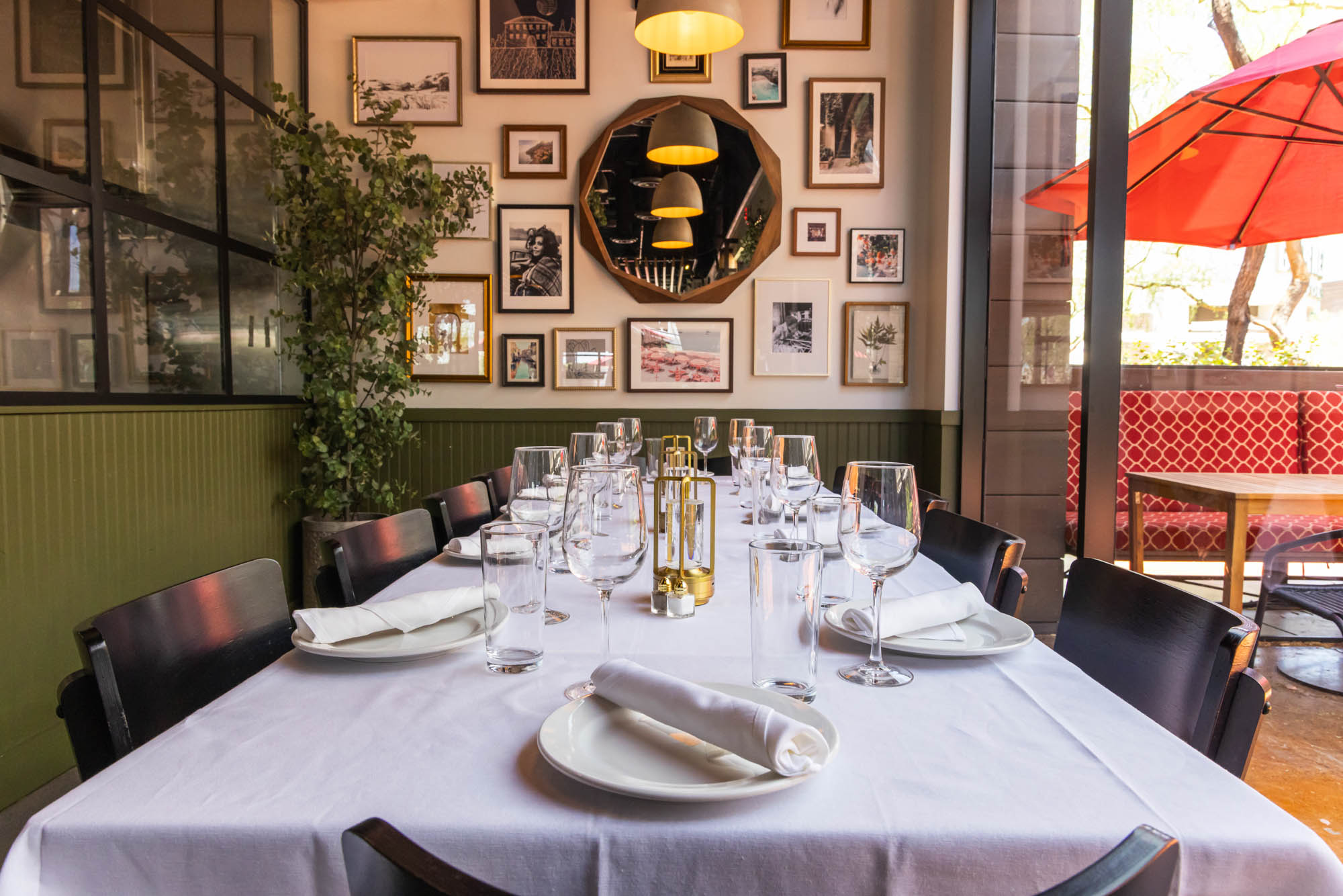 Elegant dining setup with a long, white-clothed table, neatly arranged plates, glasses, and napkins