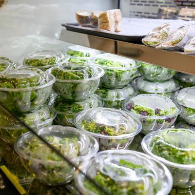 Grab-and-go prepared leafy salads packaged in clear plastic bowls.