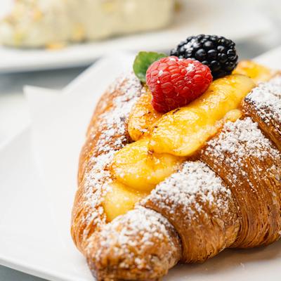 Croissant with custard filling, berries, and powdered sugar.