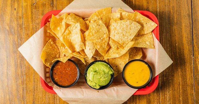 Corn chips, guacamole and hot sauce dips, top view