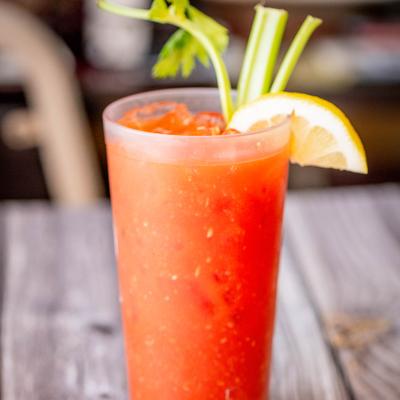 Bloody Mary cocktail garnished with celery stick and slice of lemon.