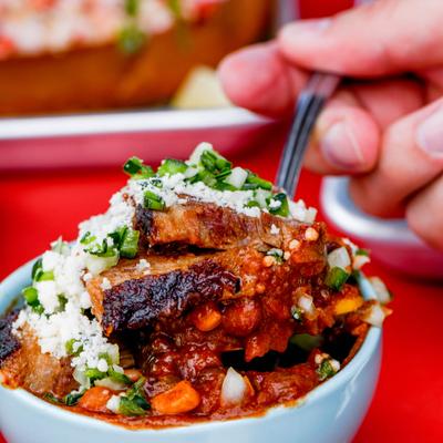 Closeup of a hand holding a spoon with Brisket chili