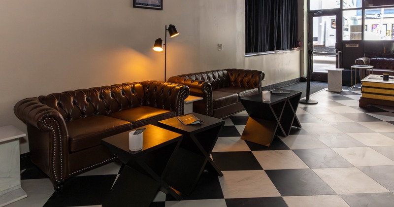Cozy room with leather sofas, checkered floor, and warm lighting.
