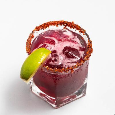 Purple Margarita cocktail garnished with lime wedge and spiced rim.