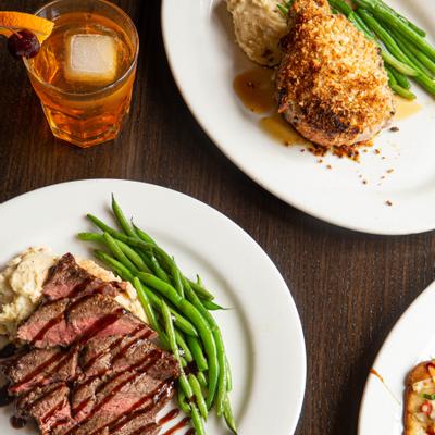 Grilled flank steak, breaded pork chop, and an Old Fashioned cocktail