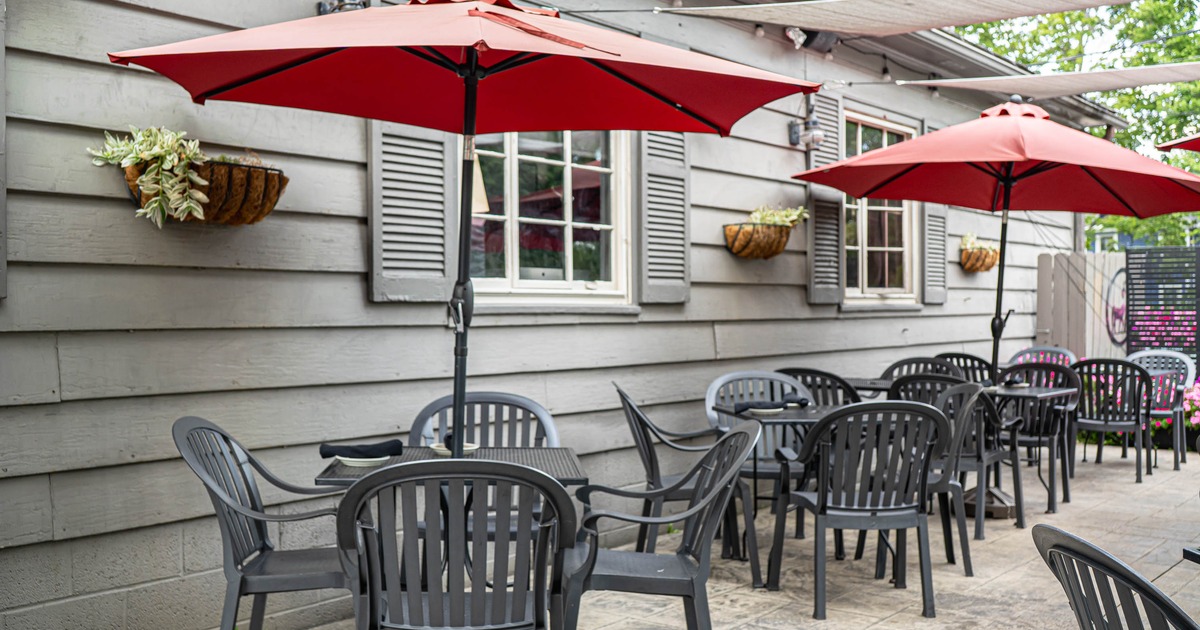 Outdoor café patio with black tables and chairs, red umbrellas