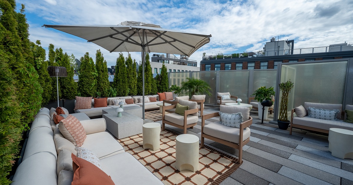 Modern rooftop lounge and outdoor seating area with cushioned sofas, lounge chairs, and low tables