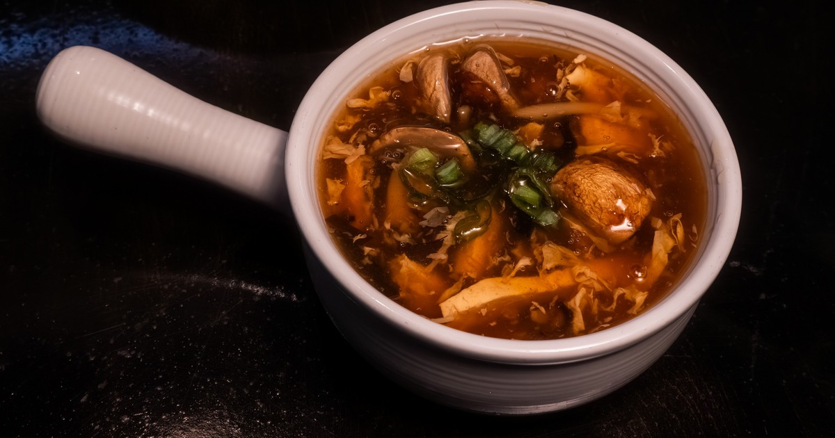Hot and sour soup served in a whit bowl with a handle, close-view