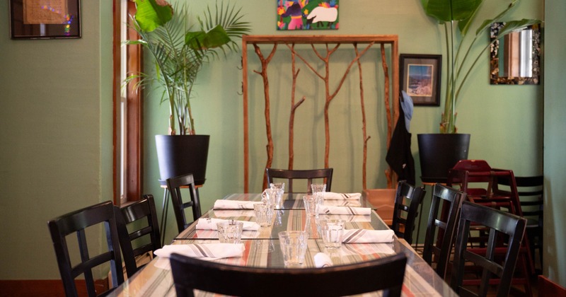 A cozy restaurant interior featuring a glass dining table set with tumblers and napkins