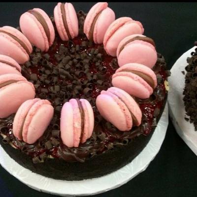 Chocolate cake adorned with pink macarons and chocolate shavings on top.