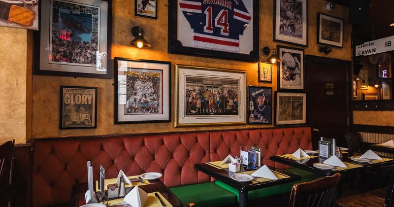 Cozy pub interior with banquette seating, set tables, and memorabilia on walls