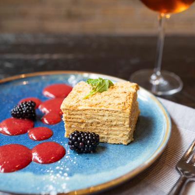 Multi-layered honey cake on plate with glass of amber wine