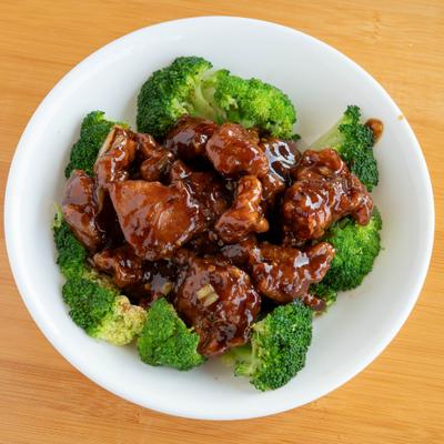 General Tso Chicken served in a white bowl with florets of broccoli.