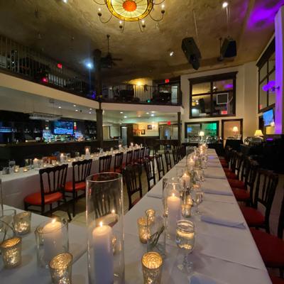 Interior, long dining tables arranged for a celebration with fine tableware and decoration.